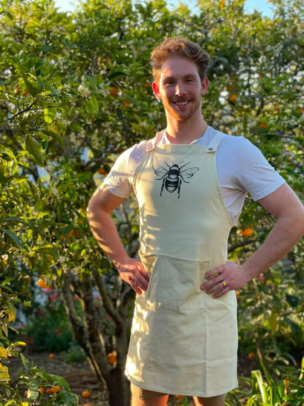 Newbee Meadery co-founder Harry Oram wearing a bee apron in a sunlit garden